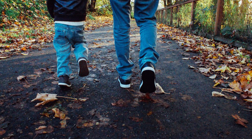 Två par ben promenerar på en höstväg.
